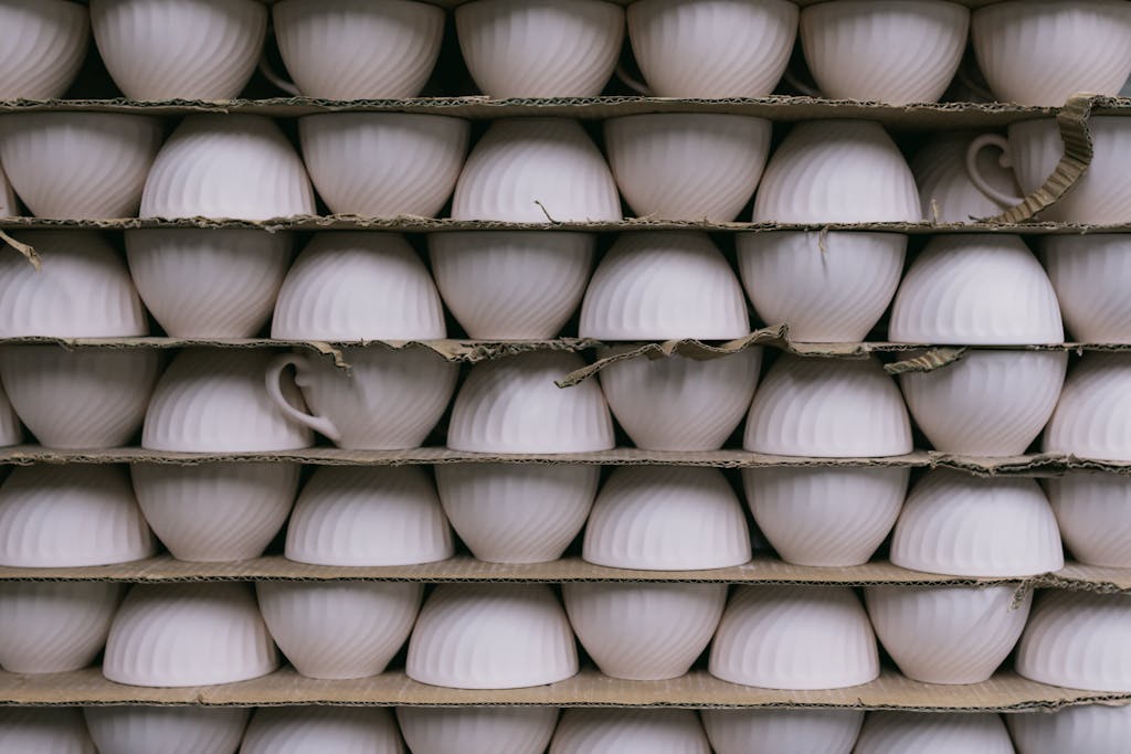 Multiple ceramic cups stacked in rows on shelves, ready for packaging or sale.